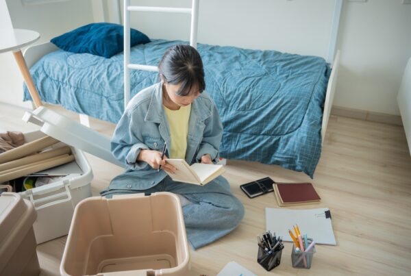 StudentAsianWomanOrganizeRoomUnpackInDormRoomCollege