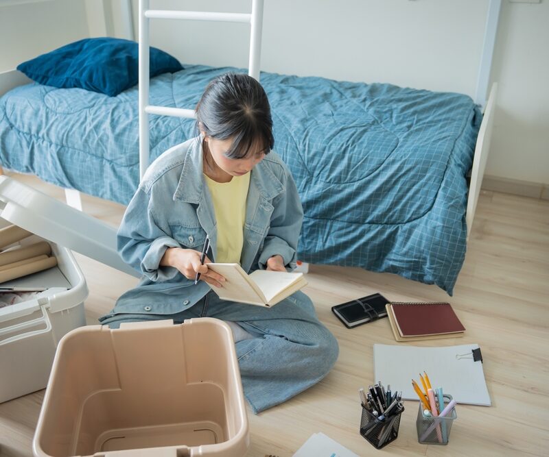 StudentAsianWomanOrganizeRoomUnpackInDormRoomCollege